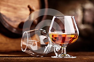 Two glass of Cognac and old oak barrel defocussed