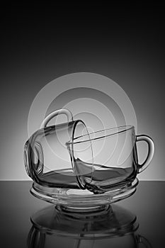 Two glass cup for tea and an empty saucer on a black background