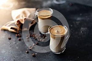 Two glass cups with Dalgona frothy coffee trend korean drink latte espresso with coffee foam on black background