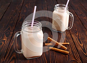 Two glass cups of hot cocoa with milk, cinnamon and straw tube