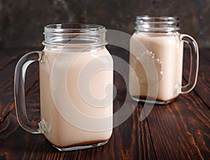 Two glass cups of hot cocoa with milk on wooden table