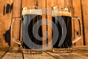 Two glass of fresh dark beer on wooden table