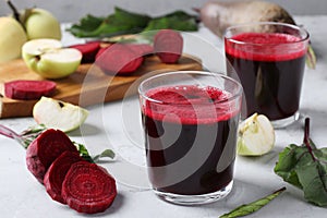 Two glass of fresh juice with beetroot and apples. Chopped beet and apples on gray table. Close up. Horizontal format