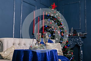 Two glass glasses with champagne on the festive table. Against the background of New Year`s decorations. Christmas tree