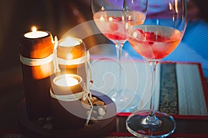 Two glass glasses with champagne and lighted candles. Evening romantic atmosphere.