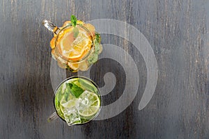 Two glass glasses with homemade lemonade from lime and lemon on a rustic black wooden background