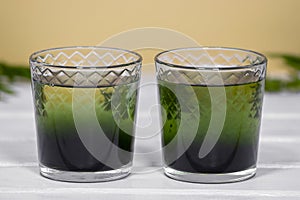 Two glass with Green Chlorophyll on white table, Orange Background. Antioxidant drinks, Superfood