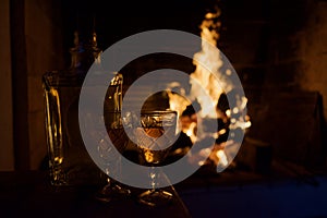 Two glass mugs of hot drink or alcoholic drink in front of warm fireplace.