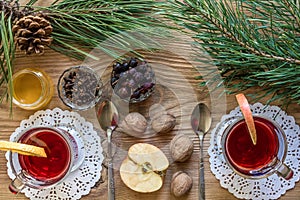 Two glass of mulled wine with cinnamon sticks, slice of oranges and apple, star anise on a wooden table