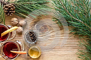 Two glass of mulled wine with cinnamon sticks, slice of oranges and apple, star anise on a wooden table