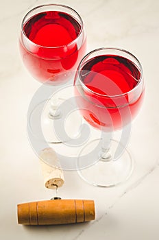 Two glass of red wine and corkscrew/Two glass of red wine and wooden corkscrew on white background. Top view