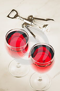 Two glass of red wine and corkscrew on white background/ Two glass of red wine and wooden corkscrew on white background. Top view