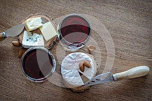 Two glass of red wine with few pieces of cheese at wooden background. top view