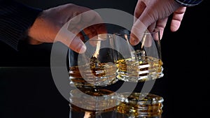 Two glass tea cups clank, slow motion against dark background, biting frost evening, outdoor shot. Couple hands in