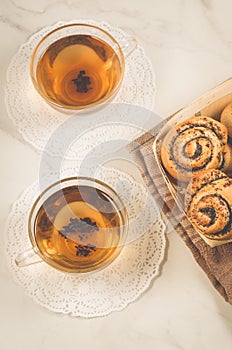 two glass tea and roll with poppy in a wooden basket/two glass tea and roll with poppy in a wooden basket on a white table, top