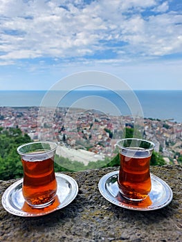 Two glass teacups with hot Turkish tea against the city skyline.