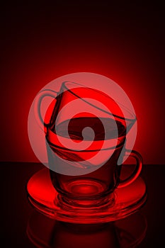 Two glass transparent cup with tea and saucer on a red background