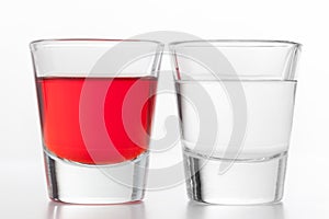 Two glasses of alcohol. One red flavoured, the other clean vodka.