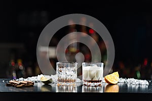 Two glasses of alcoholic drinks with ice on the table. With slices of lime and orange.