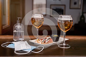 Two glasses of beer and two medical protection masks on a bar counter during the new normal of covid 19 photo