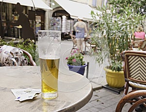 Two glasses of beer stand on a table in a street cafe with bills for payment, selective focus