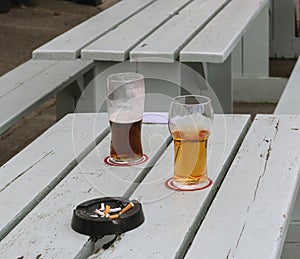 Two glasses of beer on a table outdoor.