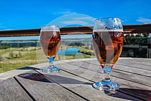 Two glasses of beer on a wooden table at outside area, New Zealand