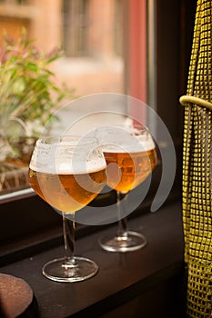 Two glasses with Belgian beer on the window