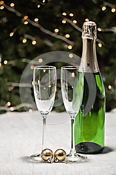 Two glasses and a bottle of champagne is on a festive tablecloth