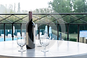 Two glasses and bottle of red wine on the balcony of vacation house