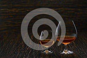 Two glasses of brandy or cognac  on a wooden table with copy space
