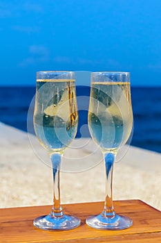 Two glasses with champagne against a sea in the evening, luxury resort with sea view, romantic vacation