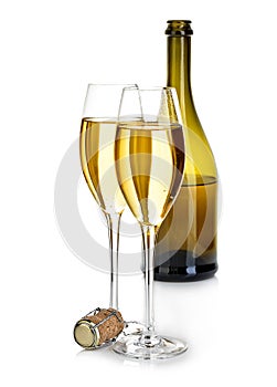 Two glasses of champagne on the background of brown bottles close-up isolated on a white. Festive still life.