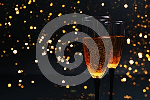 Two glasses of champagne on a black background with New Year`s lights. Christmas concept. background for your design.