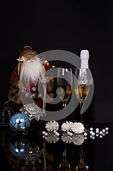 Two glasses champagne, bottle, Santa Claus and Christmas decoration
