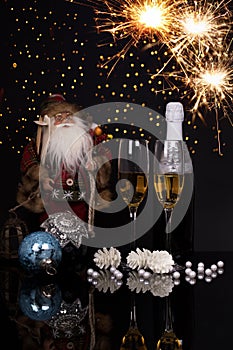 Two glasses champagne, bottle, Santa Claus and Christmas sparkle