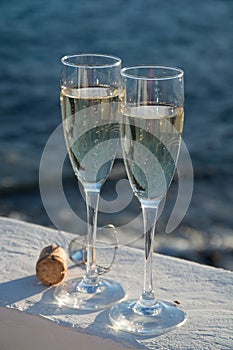 Two glasses with champagne or cava served outside on terrace, lu