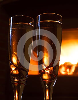 Two glasses of champagne close up in front of fire