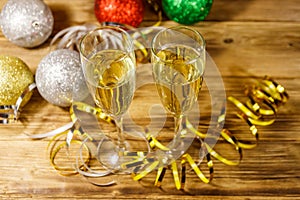 Two glasses of champagne and festive Christmas decorations on wooden table