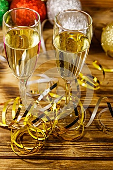 Two glasses of champagne and festive Christmas decorations on wooden table. Christmas and New Year celebration