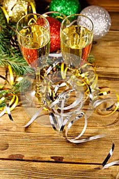 Two glasses of champagne and festive Christmas decorations on wooden table. Christmas and New Year celebration