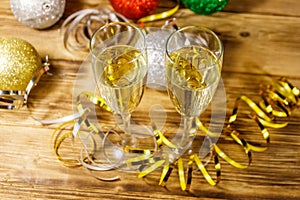 Two glasses of champagne and festive Christmas decorations on wooden table. Christmas and New Year celebration