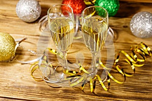 Two glasses of champagne and festive Christmas decorations on wooden table. Christmas and New Year celebration