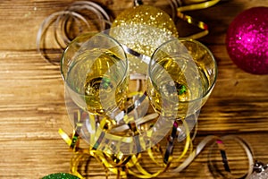 Two glasses of champagne and festive Christmas decorations on wooden table. Top view. Christmas and New Year celebration