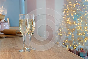 Two glasses of champagne on a kitchen. Christmas New year background and decoration, light bokeh effect and light garland
