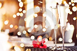 Two glasses of champagne with red flower in a spa lounge. Spa time concept. Spa lounge area. . Bold festive bokeh