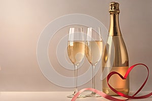two glasses of champagne, red heart-shaped ribbon with space for text on a light background, valentine\'s day