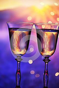Two glasses with champagne sparkling wine on a festive background with lights and bokeh.