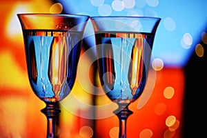 Two glasses with champagne sparkling wine on a festive background with lights and bokeh.