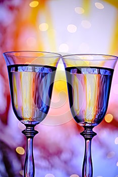 Two glasses with champagne sparkling wine on a festive background with lights and bokeh. Atmosphere of celebration, magic and happ